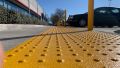 Concrete curb ramp with detectable warning surface connecting a commercial parking area to a sidewalk
