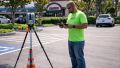 Contractor using a digital level to measure the pavement slope in an accessible parking area